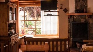 A cozy room with a wooden bench, a fireplace, and a large window with a view of greenery.