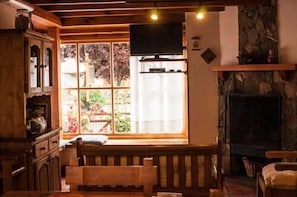 A cozy room with a wooden bench, a fireplace, and a large window with a view of greenery.