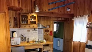 A room with a bed, a small kitchenette, and a door leading to another room.