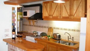 A kitchen with wooden cabinets, a microwave, a gas stove, and a sink.