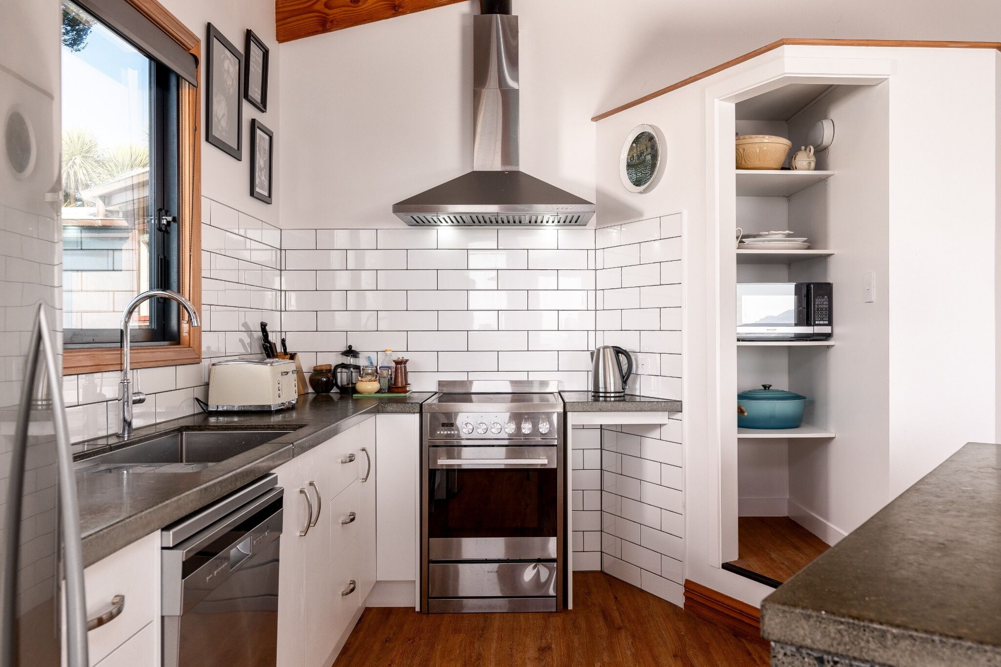 Une cuisine moderne avec un dosseret de carreaux blancs, des appareils en acier inoxydable et un plancher en bois.