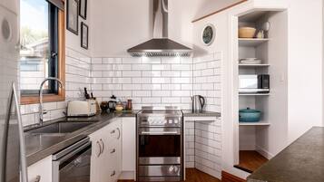 Une cuisine moderne avec un dosseret de carreaux blancs, des appareils en acier inoxydable et un plancher en bois.