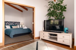 Une chambre à coucher avec un lit, une table de chevet, une télévision et une plante.