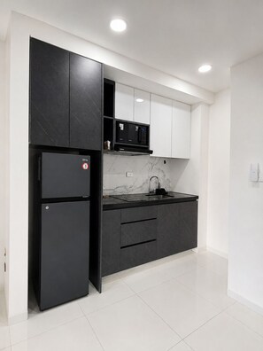 Una cocina moderna con un refrigerador negro, un microondas y un salpicadero de mármol.