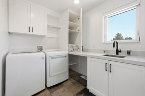 A laundry area with two washing machines, a sink, and a window. - The Perfect Pace by Park City Vacations (Park City)