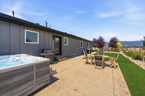Eine moderne Außenpatio mit Whirlpool, Gartenmöbeln und Blick auf die Landschaft.