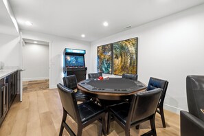 A room with a round table, black leather chairs, a gaming console, and two abstract paintings. - The Perfect Pace by Park City Vacations (Park City)