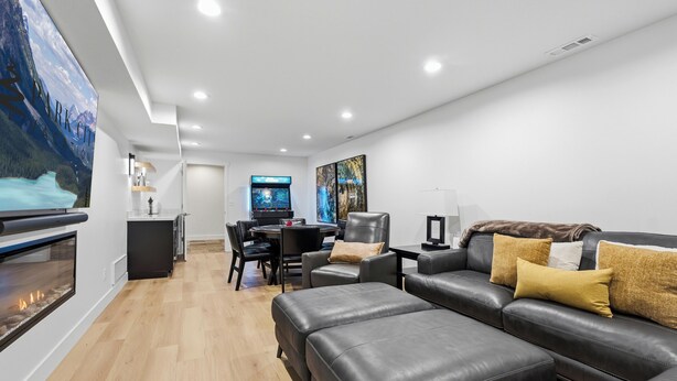 A modern living room with a fireplace, leather sofa, and a flat-screen TV. - The Perfect Pace by Park City Vacations (Park City)