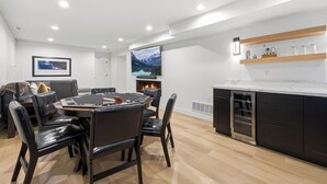 A modern kitchen with a central island, a dining area with a round table and chairs, and a flat-screen TV mounted on the wall. - The Perfect Pace by Park City Vacations (Park City)