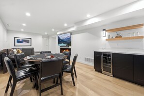 A modern kitchen with a central island, a dining area with a round table and chairs, and a flat-screen TV mounted on the wall. - The Perfect Pace by Park City Vacations (Park City)
