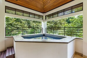 A hot tub with a view of lush greenery through large windows. - 6 Bdr Penthouse with Plunge Pool and Beach Club Access! (Tamarindo)