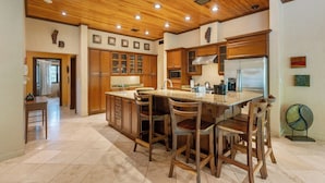 Una cocina con armarios de madera, un refrigerador de acero inoxidable y una isla central con sillas.