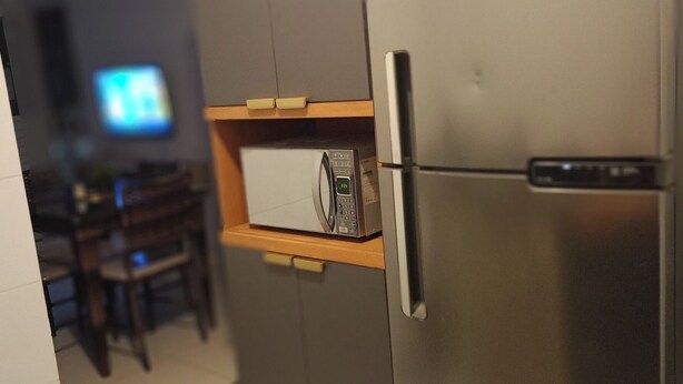 Una cocina con microondas integrado, un refrigerador y un armario de madera.