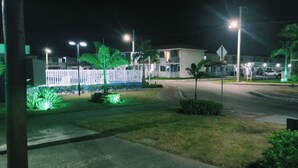 Vista nocturna de una zona residencial con casas, calle y farolas.