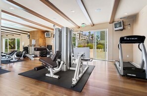 A gym with exercise equipment, a treadmill, and a television on the wall. - Panoramic Oceanview Townhome ON THE BEACH (Los Angeles)