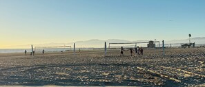 A beach volleyball court with a net, players, and a clear sky. - Panoramic Oceanview Townhome ON THE BEACH (Los Angeles)
