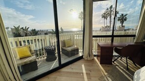 Un balcon avec vue sur l’océan, un bureau en bois et une chaise.