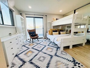 A bedroom with a bunk bed, a chair, a dresser, and a patterned rug. - Panoramic Oceanview Townhome ON THE BEACH (Los Angeles)