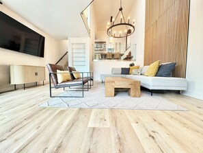 A modern living room with a sofa, two armchairs, a coffee table, and a wooden floor. - Panoramic Oceanview Townhome ON THE BEACH (Los Angeles)