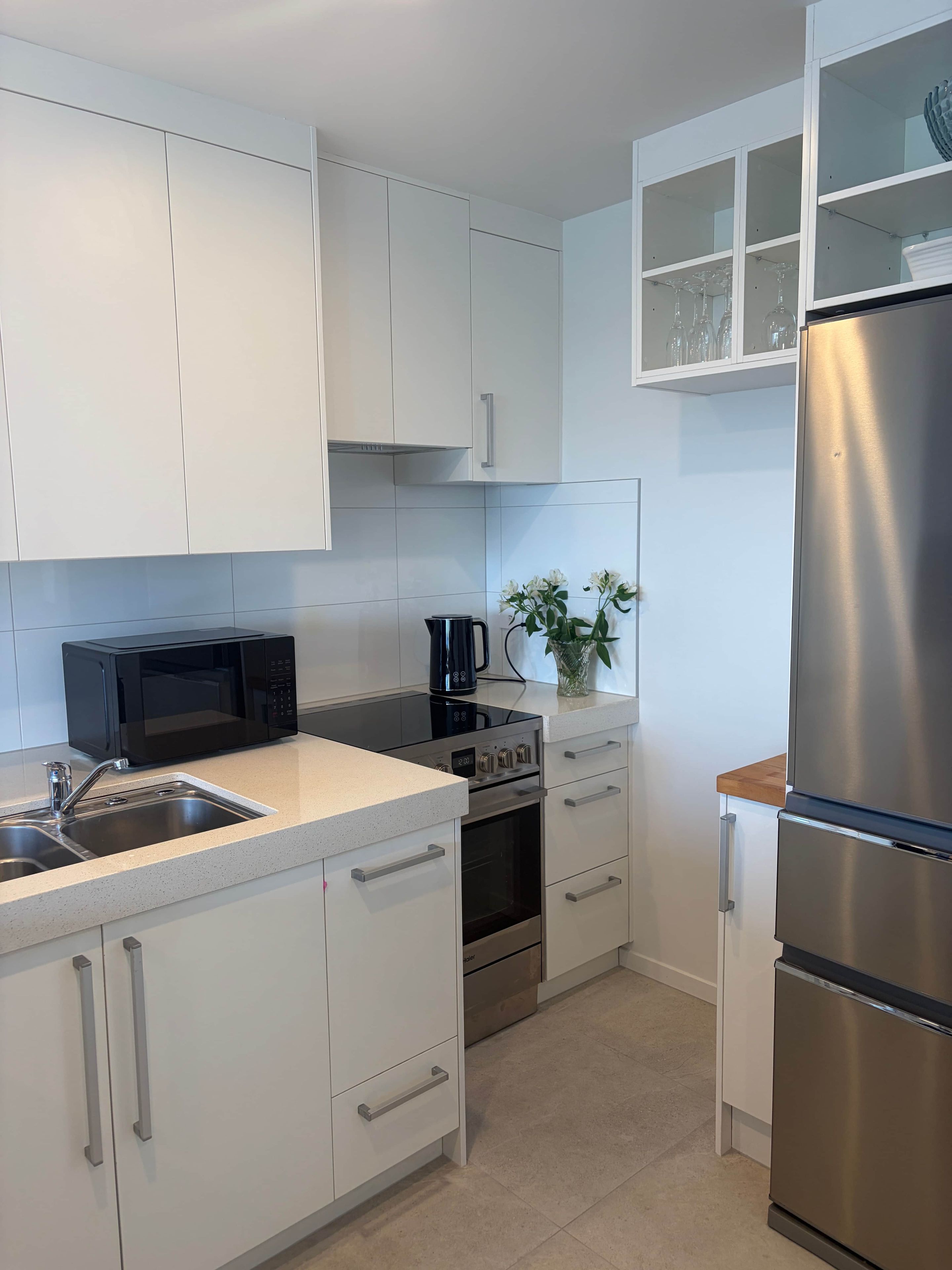 A modern kitchen with white cabinets, stainless steel appliances, and a tiled backsplash.