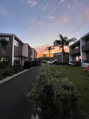 A modern residential building with a paved driveway and well-maintained landscaping. - Sandy Soul Beach Apartment (Whitianga)