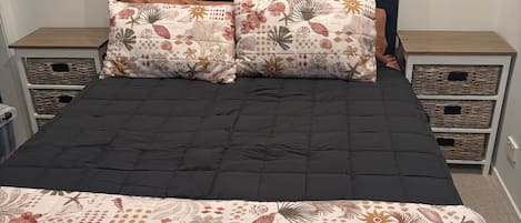 A bed with a dark headboard, two decorative pillows, and a floral-patterned bedspread.
