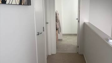 En hall med ett mattbeklätt golv, en vit dörr och en handduk som hänger på dörrhandtaget.