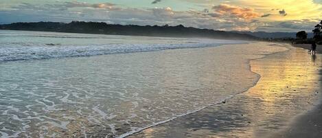 A beach with waves, a clear sky, and a distant shoreline.