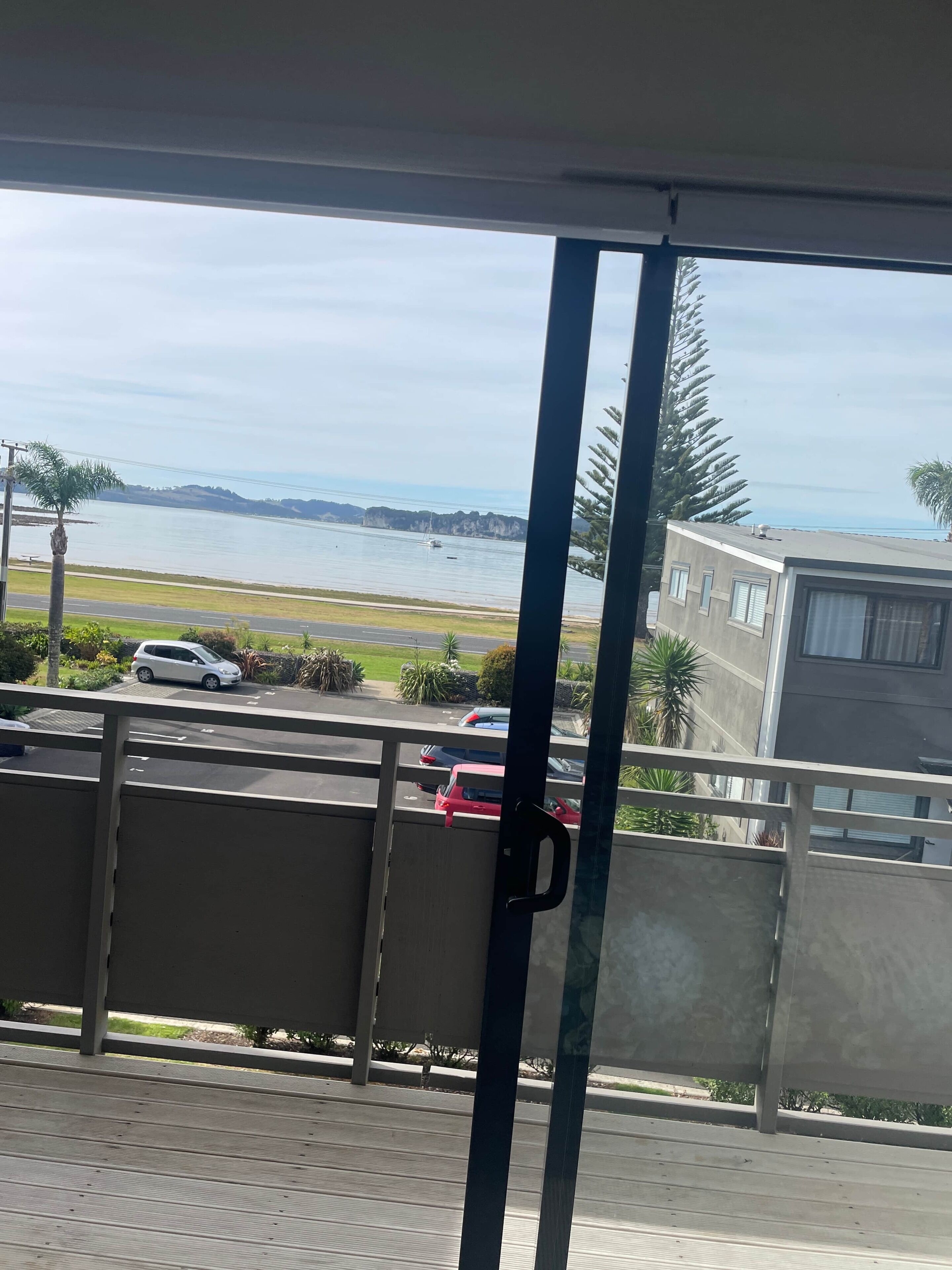 Un balcón con vista a una masa de agua, un estacionamiento y un edificio.