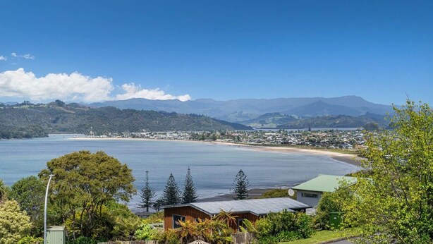 Paisagem costeira com vista clara para o mar, uma praia e uma cidade ao longe.