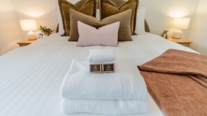 A neatly made bed with two towels, a brown towel, and two soap bars. - Stoke and Steam - the ultimate pad for adventurers (Bright)
