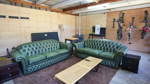 Ett rum med två gröna soffor i läder, ett träbord och ett cykelställ med flera cyklar.