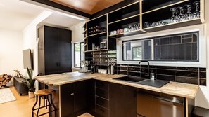 A modern kitchen with a wooden countertop, black cabinetry, and a window above the sink. - Stoke and Steam - the ultimate pad for adventurers (Bright)
