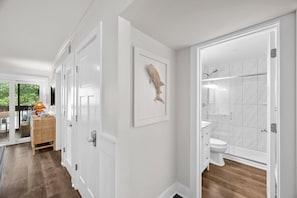 A modern bathroom with a shower, toilet, and a wall-mounted fish sculpture. - The Tidal Cottage - Beach Access + Pools (Hilton Head Island)
