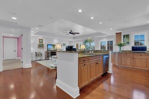 A spacious kitchen with wooden cabinets, a central island, and a ceiling fan. - Luxury Downtown Retreat | Steps to 5th Ave & Beach (Naples)