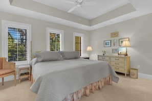 A bedroom with a bed, a chair, a nightstand, a dresser, and a ceiling fan. - Luxury Downtown Retreat | Steps to 5th Ave & Beach (Naples)