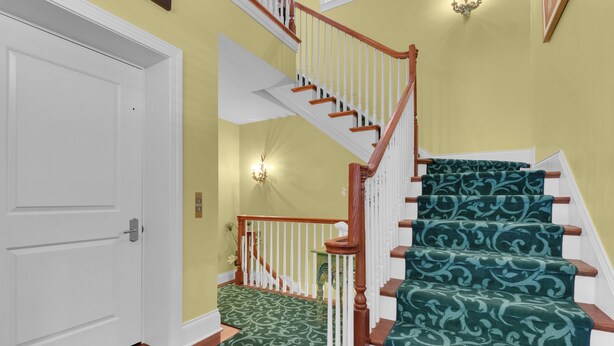 A staircase with a green patterned carpet, white walls, and a wooden handrail. - Luxury Downtown Retreat | Steps to 5th Ave & Beach (Naples)