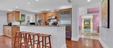 A modern kitchen with wooden cabinets, stainless steel appliances, and a central island with bar stools.