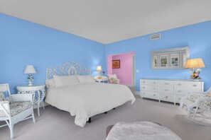 Une chambre à coucher comprenant un lit, deux tables de chevet, une commode et une chaise.