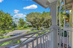 A balcony with a view of a street lined with trees and a building. - Luxury Downtown Retreat | Steps to 5th Ave & Beach (Naples)