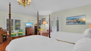 A hotel room with two beds, a chandelier, a television, a desk, a chair, and a painting on the wall. - Luxury Downtown Retreat | Steps to 5th Ave & Beach (Naples)