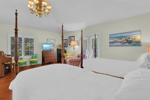 A hotel room with two beds, a chandelier, a television, a desk, a chair, and a painting on the wall. - Luxury Downtown Retreat | Steps to 5th Ave & Beach (Naples)