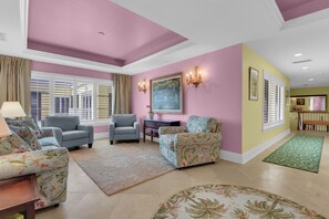 A spacious living room with a high ceiling, a large window with blinds, and a fireplace. - Luxury Downtown Retreat | Steps to 5th Ave & Beach (Naples)