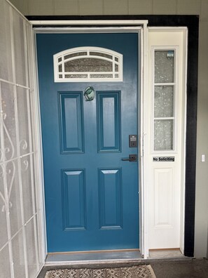 A blue door with a 'No Soliciting' sign, a small window with a decorative frame, and a doorbell. - Lovely 3-bedroom house near large dog park (Lodi)