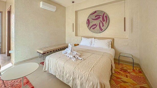 A hotel room with a bed, a round wall decoration, a bench, and a small table. - The Blue Room at Riad Timija: En-suite, Breakfast & Rooftop in the Medina (Marrakesh)