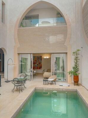 A pool area with a glass-enclosed patio, a dining table, chairs, and a lounge chair. - The Double Room at Riad Timija: En-suite, Breakfast & Rooftop in the Medina (Marrakesh)