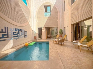 A swimming pool with lounge chairs and a glass door entrance. - The White Room at Riad Timija: En-suite, Breakfast & Rooftop in the Medina (Marrakesh)
