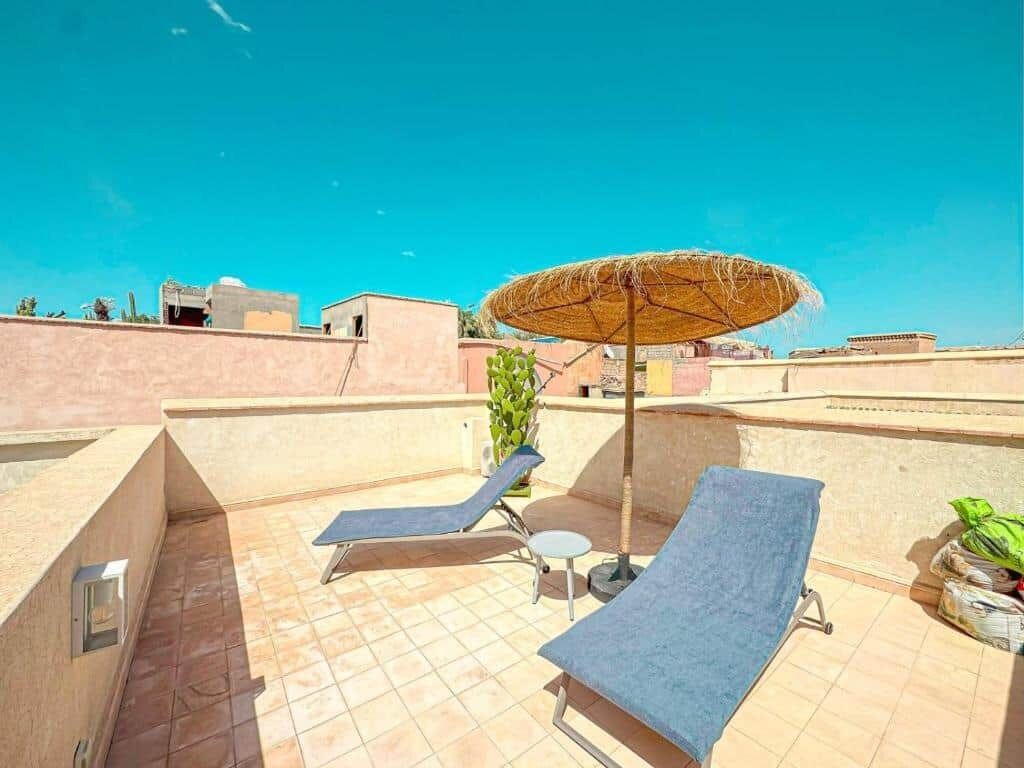 A rooftop terrace with lounge chairs and a sun umbrella.