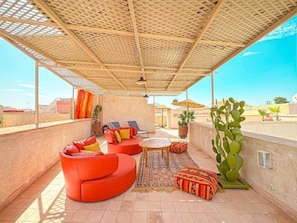 A rooftop terrace with a woven ceiling, outdoor seating, and a cactus plant. - The Red Room at Riad Timija: En-suite, Breakfast & Rooftop in the Medina (Marrakesh)