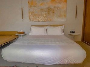 A hotel room with a large bed, a small bedside table, a round table, and a large abstract painting on the wall. - The Red Room at Riad Timija: En-suite, Breakfast & Rooftop in the Medina (Marrakesh)